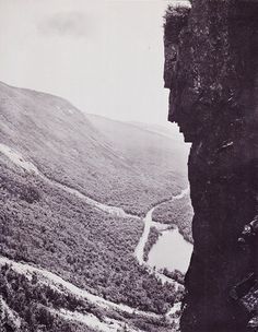 a man standing on top of a cliff next to a river