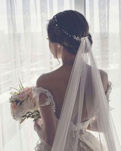 the back of a bride's wedding dress, with her veil draped over her shoulder