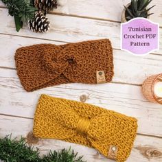 two crocheted headbands with bows on them sitting next to pine cones