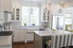 a large kitchen with white cabinets and marble counter tops, along with a breakfast nook