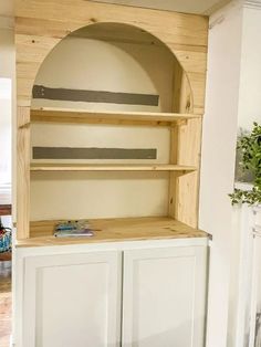 a white cabinet with shelves and drawers in a room that has a wood fireplace surround