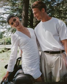 a man and woman standing next to each other in the back of a golf cart