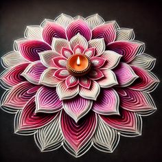 a candle is lit in the center of a flower shaped paper decoration on a black background