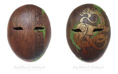 two wooden masks with designs on them are side by side, one is brown and the other is green