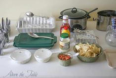 an assortment of condiments on a table with utensils and other items