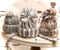 three knitted hats sitting on top of a white cake plate next to each other