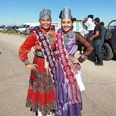 two women standing next to each other wearing crowns