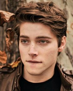 a young man with freckled hair looks at the camera while wearing a leather jacket