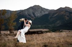 a bride and groom kissing in front of mountains