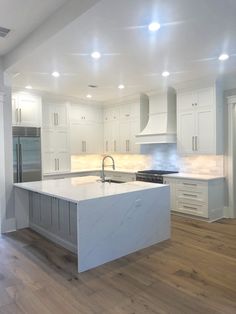 a large kitchen with white cabinets and an island in the middle of the room is lit by recessed lights