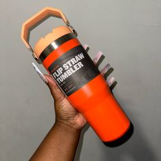 a person holding an orange and black fire extinguisher in their left hand