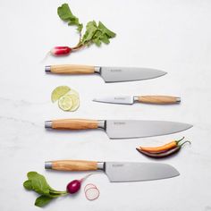 four knives are lined up next to each other with vegetables on the side and garnishes