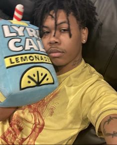 a young man with dreadlocks is holding a lemonade bottle shaped like a bag