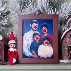 an elf with two red noses is next to a christmas tree