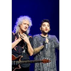 two men standing next to each other on stage with microphones in front of them