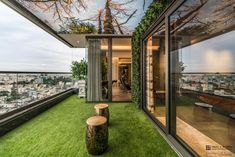 an open room with green grass on the floor and large windows overlooking cityscape