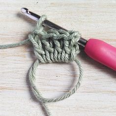 a pink crochet hook is hooked up to the end of a green rope