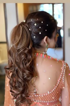 the back of a woman's head with long, wavy hair and beads on it