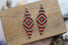 a pair of beaded earrings sitting on top of a piece of wood