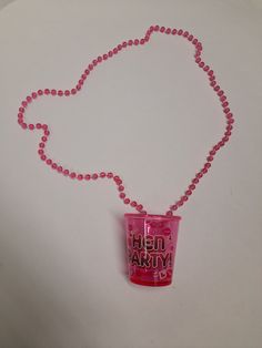 a pink plastic cup necklace on a white surface with beads and a red ball chain