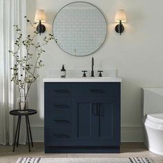 a white toilet sitting next to a blue vanity in a bathroom under a round mirror