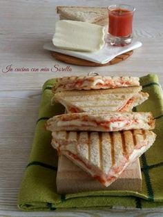 sandwiches stacked on top of each other on a wooden cutting board next to a glass of orange juice