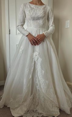 a woman in a white wedding dress standing next to a door with her hands on her hips