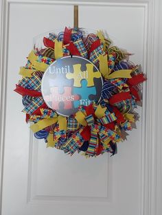 a colorful wreath with puzzle pieces hanging from it's side on the front door