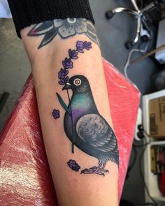 a black bird with purple flowers on it's arm