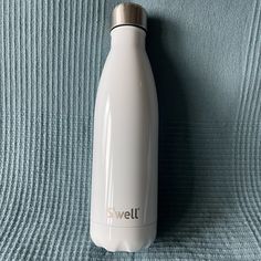 a white water bottle sitting on top of a blue blanket next to a metal lid