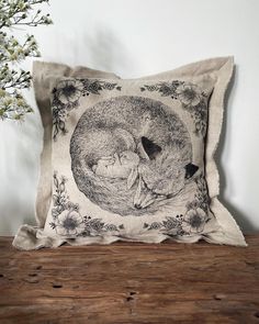 a pillow with a drawing of a woman and a cat on it sitting on a wooden table