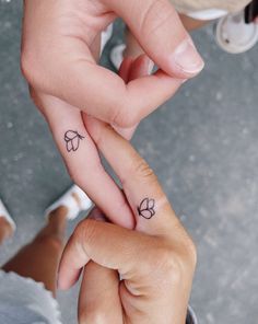 two people holding hands with tattoos on their fingers and one has a clover tattoo on the middle finger