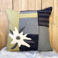 a gray and black pillow sitting on top of a white furnishing floor next to a wooden wall