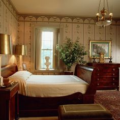 a bed room with a neatly made bed next to a window and a chair in front of it