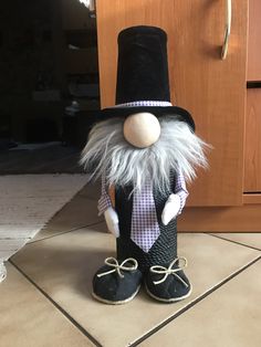 a close up of a stuffed animal wearing a top hat and tie on the floor