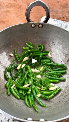 green beans being cooked in a frying pan on the stove top with garlic and seasonings