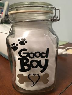 a glass jar with a dog's paw and heart on the lid that says good boy