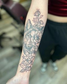 a woman's arm with a wolf and flowers tattoo on it