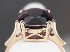 Always popular and never out of style, this vintage ring is a modestly sized cocktail piece that is easy to wear day or evening! The center stone is a bright grape garnet with sumptuous flashes of violet, cabernet, and berry pink. The airy design of the undercarriage lets plenty of light flow through the stone! Metal: 14K Yellow Gold Gem: Grape Garnet 7.11 Carats Gem Measurements: 10.5 x 14.4 mm, Oval Ring Size: 7.50 Marks: "14K" Stamped on the inside band Elegant Purple Ruby Ring Round Shape, Elegant Purple Ruby Ring Round Cut, Purple Ruby Ring For Formal Occasions, Timeless Solitaire Ruby Ring For Formal Occasions, Timeless Solitaire Ruby Ring For Formal Events, Classic Burgundy Ruby Ring For Formal Occasions, Formal Garnet Burgundy Ring, Formal Burgundy Garnet Ring, Classic Burgundy Jewelry For Formal Occasions