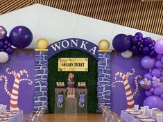 an entrance to wonka's golden ticket restaurant decorated with purple balloons and candy canes