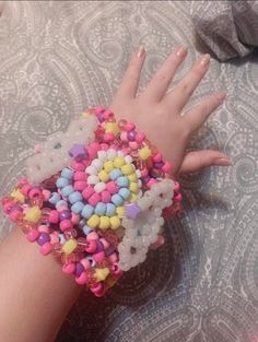 a person's hand with colorful beads on it and a bracelet made out of balloons