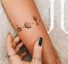 a woman's arm with tattoos on it and books, wine glasses, and other items