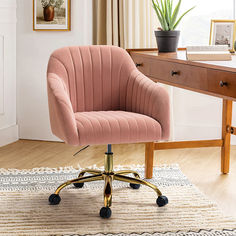 a pink velvet office chair sitting on top of a wooden desk next to a potted plant