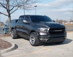 a gray ram truck parked in a parking lot next to a tree with no leaves on it