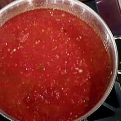 a pan filled with red sauce sitting on top of a stove