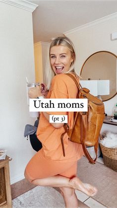 a woman in an orange dress is holding a brown purse and smiling at the camera