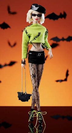 a barbie doll dressed in black and green with bats flying around her, holding an umbrella