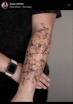 a woman's arm with flowers on it and an apple watch in the background