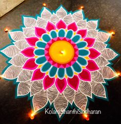 a lit candle is placed on the ground in front of a decorated flower design with lights