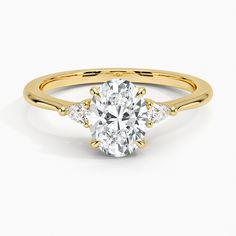 a yellow gold engagement ring with an oval cut diamond and side stones on the band